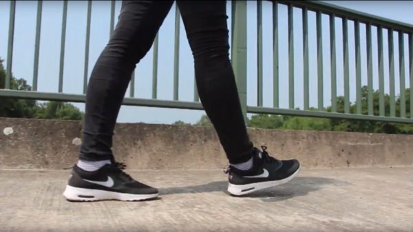 Foto von Beinen die vor einem Brückengeländer langlaufen